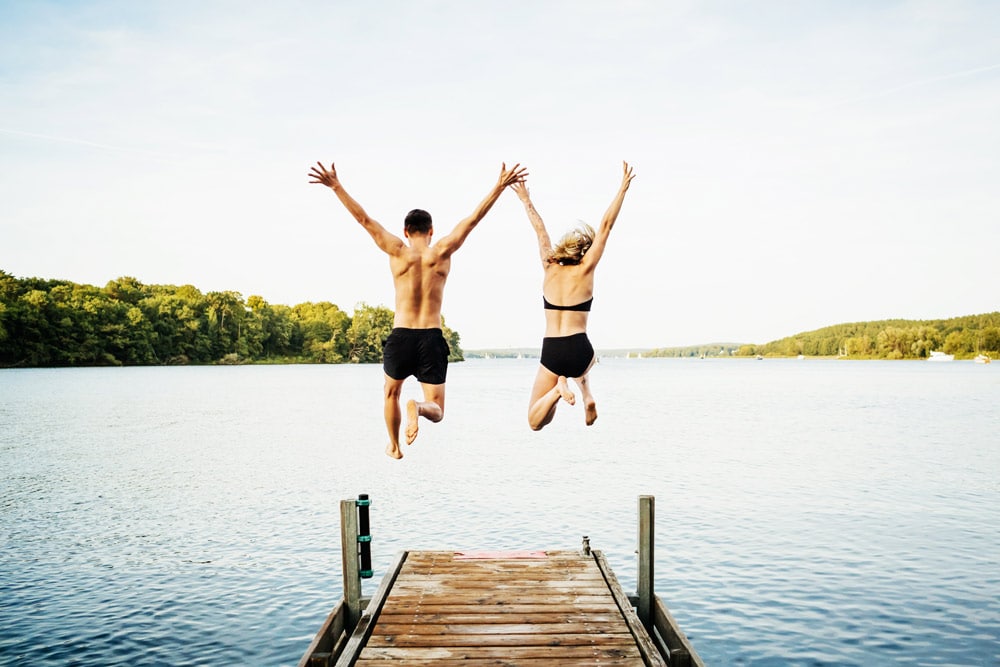 Sommerferien Mann und Frau springen in Wasser