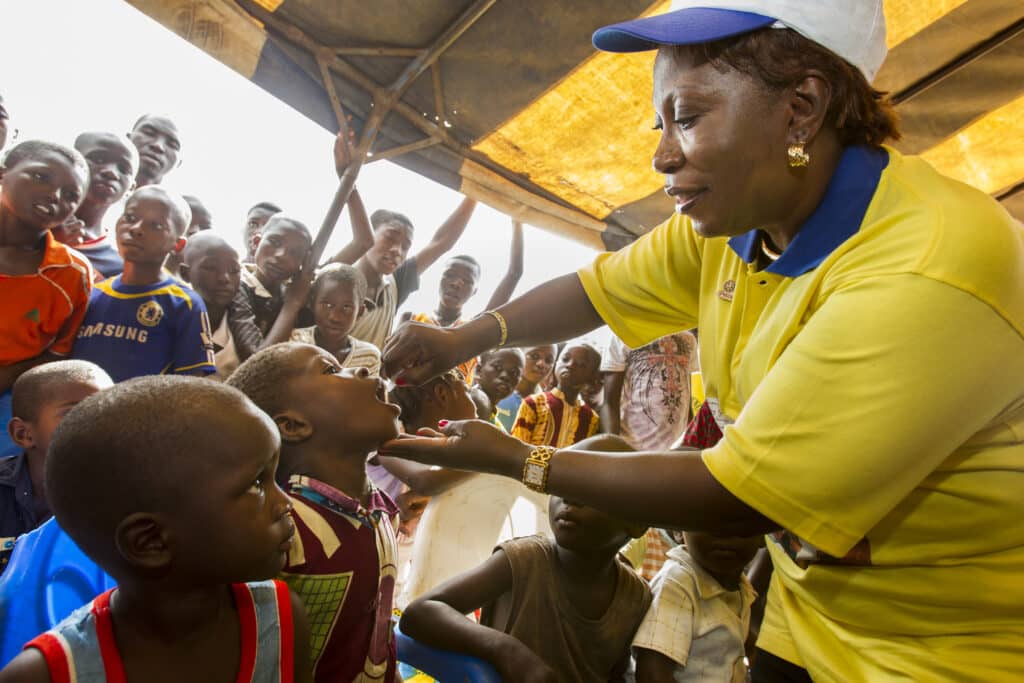 Rotarierin Marie-Irene Richmond-Ahoua, Vorsitzende des PolioPlus-Ausschusses der Elfenbeinküste, impft ein Kind mit Polio-Impfstoff während einer Begrüßungszeremonie zum Auftakt eines nationalen Impftages im Dorf Messikro, Elfenbeinküste Rotarierin Marie-Irene Richmond-Ahoua, Vorsitzende des PolioPlus-Ausschusses der Elfenbeinküste, impft ein Kind mit Polio-Impfstoff während einer Begrüßungszeremonie zum Auftakt eines nationalen Impftages im Dorf Messikro, Elfenbeinküste