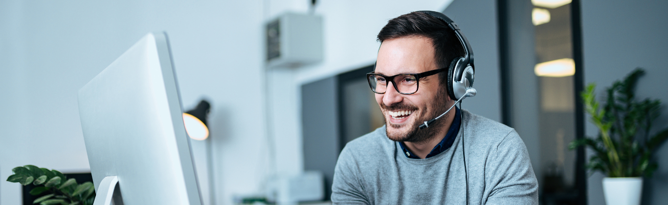 Verkaufsinnendienst – der versteckte Champion des Vertriebs - Mann lächelnd mit Headset am Computer
