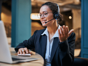 Telefontraining Schweiz «Telefon Excellence» - Lächelnde Mitarbeiterin mit Headset im Telefongespräch am Laptop