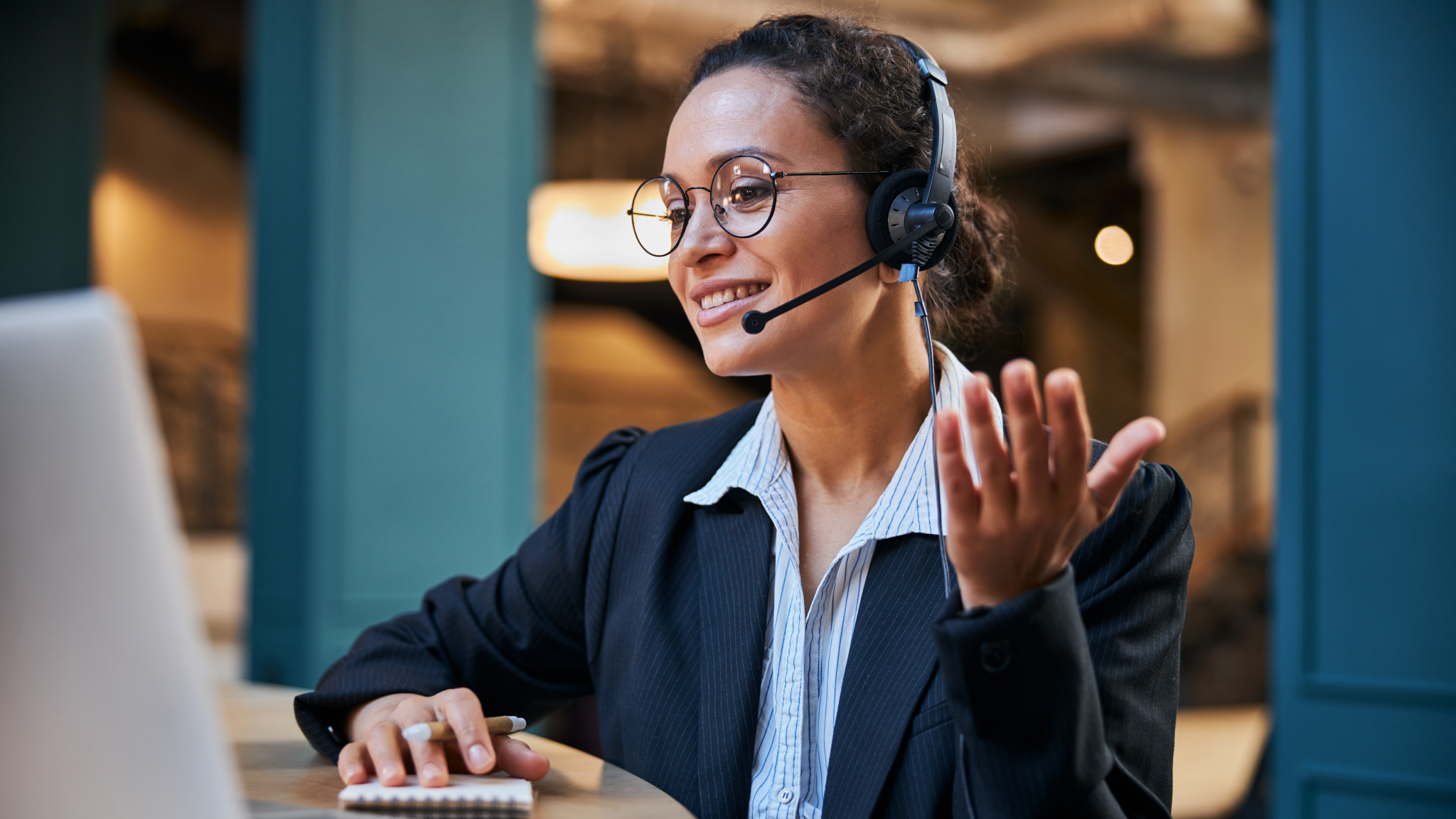 Telefontraining Schweiz «Telefon Excellence» - Lächelnde Mitarbeiterin mit Headset im Telefongespräch am Laptop