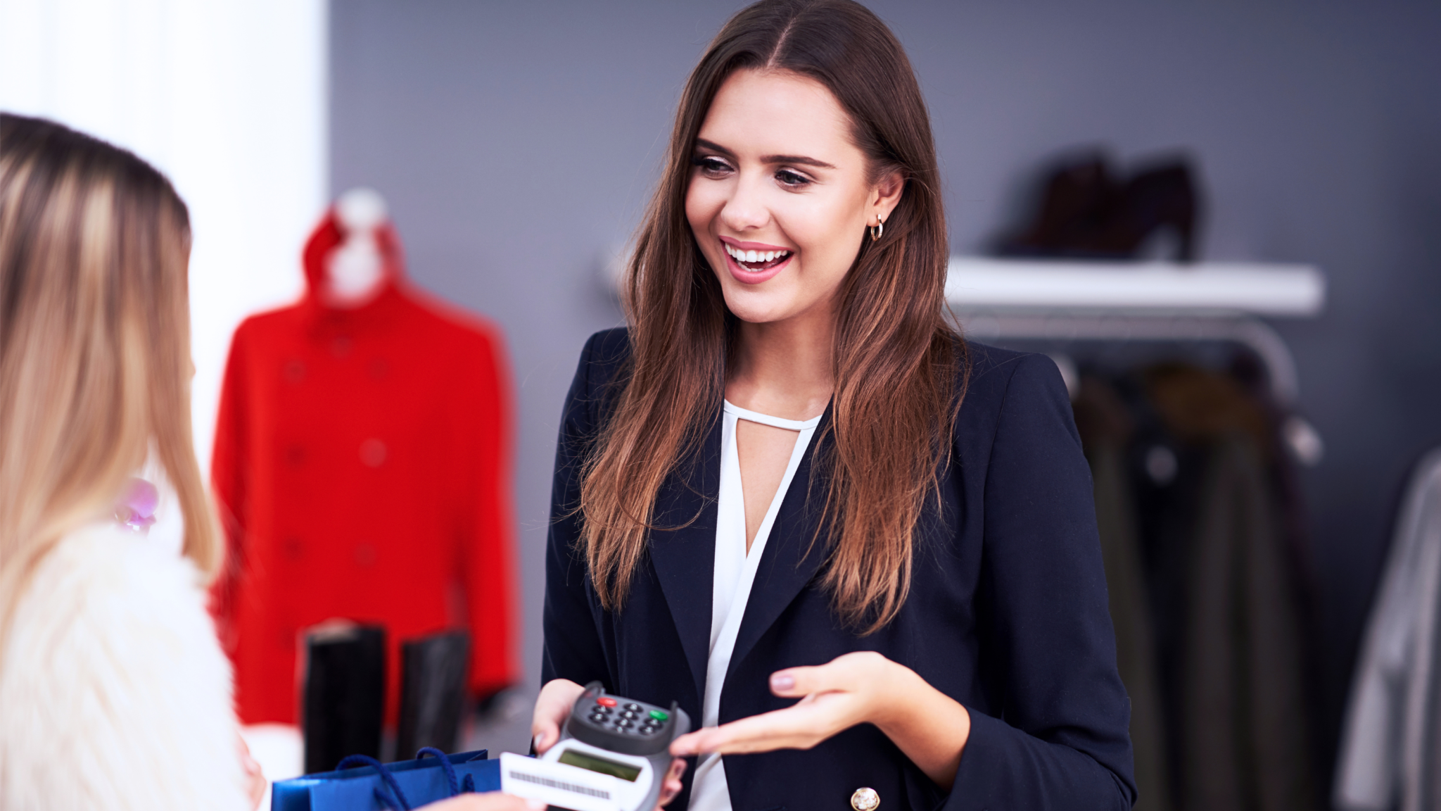 Verkaufstraining «Verkaufen am POS» - Lächelnde Verkäuferin mit Kundin an der Kasse einer Boutique